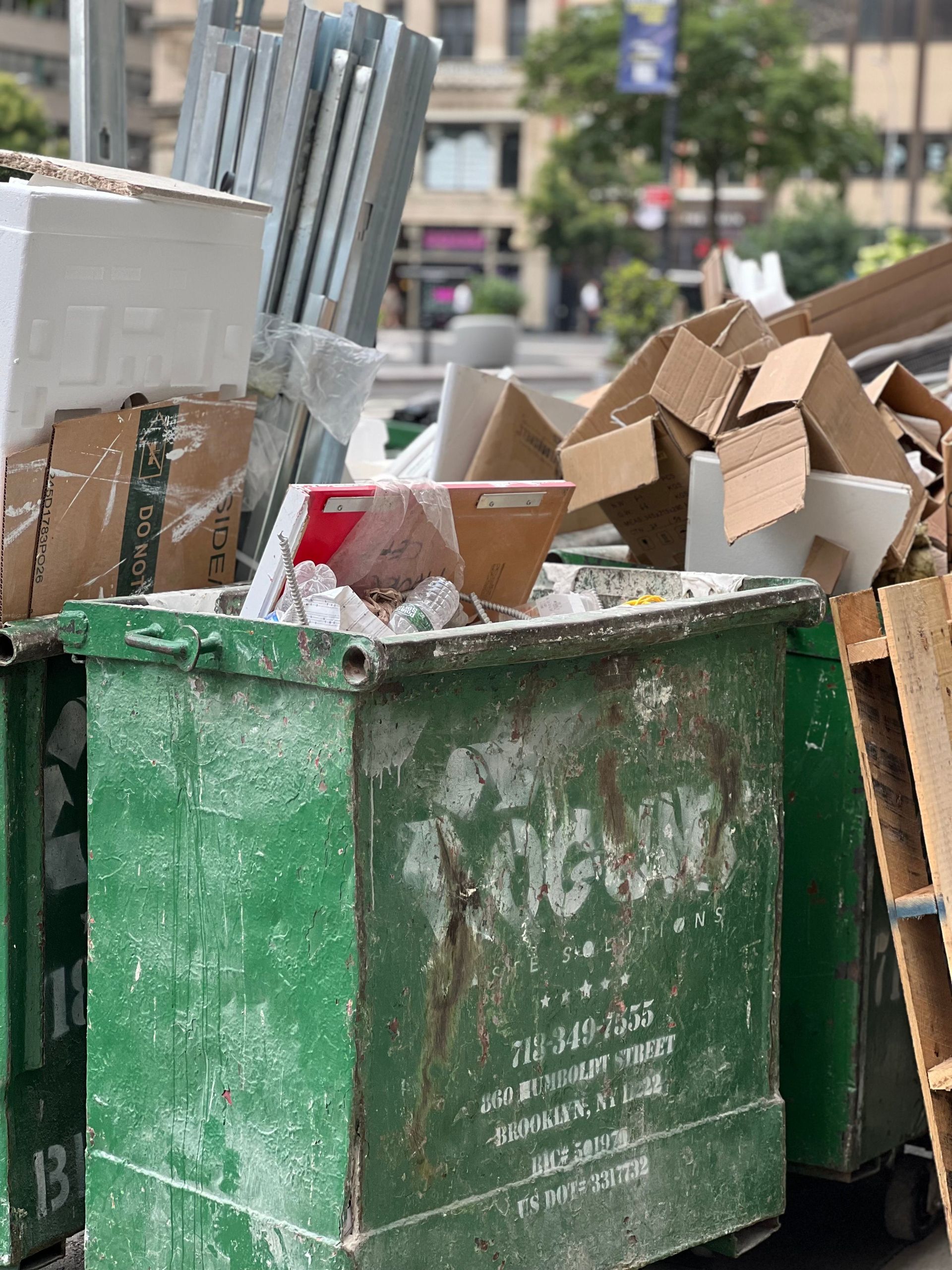 Overflowing dumpster with cardboard and various waste in urban setting.